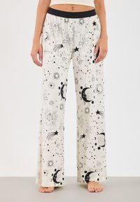 Väljalõigatud leveäljalõikega olohousut vaalean kermaan, joissa musta taivaallinen ja astrologinen kuviointi, joustava vyötärönauha, sileä kangaspinta.