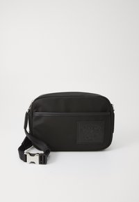 Borsa a tracolla in nylon nero con un patch logo testurizzato, chiusura con zip e tracolla regolabile con gancio in tonalità argento.