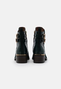 Botines de cuero verde oscuro con texturización de cocodrilo, que presentan dobles acentos de hebilla dorada y un tacón bajo apilado.