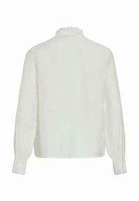 Bílá dlouhá halenka s texturovaným povrchem, s volánkovým límcem a manžetami na knoflíky. Minimalistický design, bez viditelných vzorů.