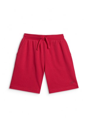 Chłopiec stoi z rękami w kieszeniach, ubrany w granatowy wielowarstwowy T-shirt, czerwone szorty, białe skarpetki i białe trampki na szarym tle.