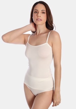 Beige tank top with adjustable straps, smooth fabric, and fitted design. Paired with matching high-waisted shorts for a seamless look.
