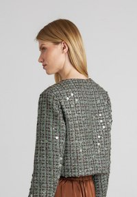 Graugrüne, kurz geschnittene Jacke mit strukturiertem Muster, verziert mit Pailletten, mit einem runden Ausschnitt und langen Ärmeln.