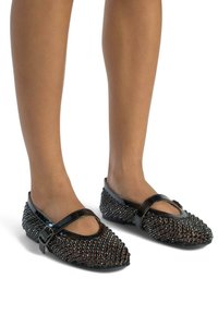 Czarne płaskie buty z wystającym wzorem, z błyszczącym wykończeniem z lakierowanej skóry, pasek na podbiciu i zaokrąglony czubek. Teksturowane ozdoby podkreślają styl.