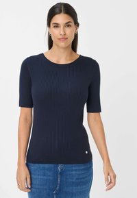 Top corto a maniche corte in maglia ribbed di colore blu navy, con scollatura rotonda e piccolo logo sul bordo, abbinato a jeans denim blu.