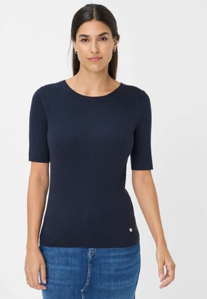 Marineblå ribbet strik top med korte ærmer, rund halsudskæring og lille logo detalje ved sømmen, parret med blå denim jeans.