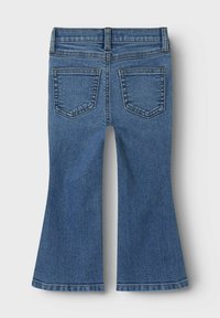 Jeans en denim évasés de bleu moyen. Présentent des poches arrière standard, des accents de couture et une finition lisse. Coupe légèrement ample en bas.