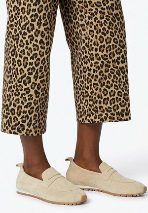 Onderbenen met cropped broek in luipaardprint en beige instap suède loafers met rubberen zolen.