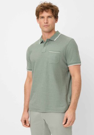 Polo shirt en tricot vert avec manches courtes, col, accents blancs et poche sur la poitrine. Le matériau semble texturé.