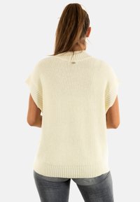 Maglione leggero a maglia con maniche corte, texture a coste e orlo arrotondato. Dettaglio del marchio discreto sulla parte posteriore del collo.