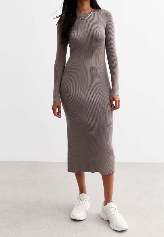 Femme portant une robe midi ajustée à manches longues en maille côtelée couleur taupe et des baskets blanches sur un fond uni.