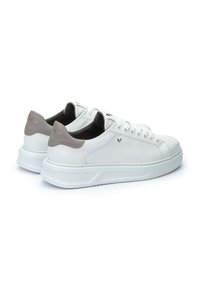 Sneaker di pelle bianca con dettagli grigi, punta rotonda, lacci davanti, colletto imbottito e suola in gomma testurizzata, con un branding discreto.