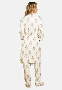 Blumen-Pyjama-Set bestehend aus einem langärmeligen, mit Gürtel versehenen Morgenmantel und passenden Hosen. Cremefarbener Hintergrund mit orangefarbenen und blauen Blumenmustern. Weicher Stoff.
