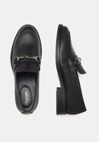 Mocassini in pelle nera con punta arrotondata, dettaglio della fibbia in argento, cuciture texturate e suola piatta con righe. Marchio visibile all'interno.