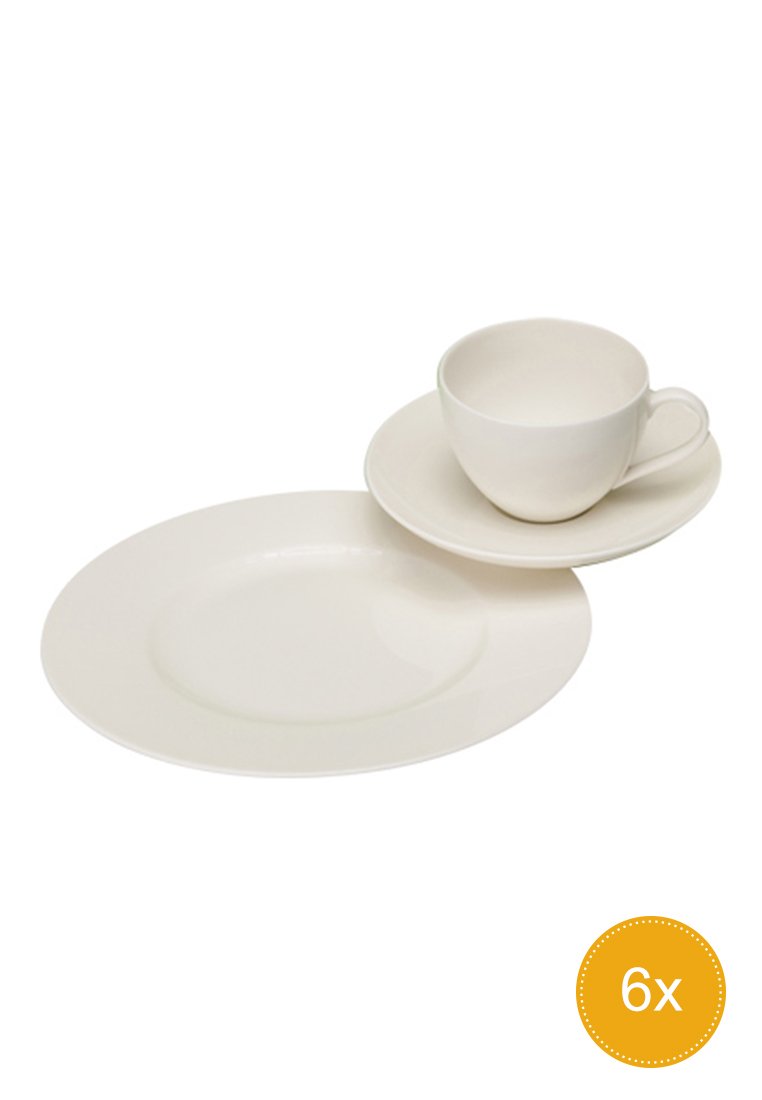 Weißer Keramikbecher mit Henkel auf passendem Unterteller, platziert neben einem passenden runden Teller vor einem weißen Hintergrund.