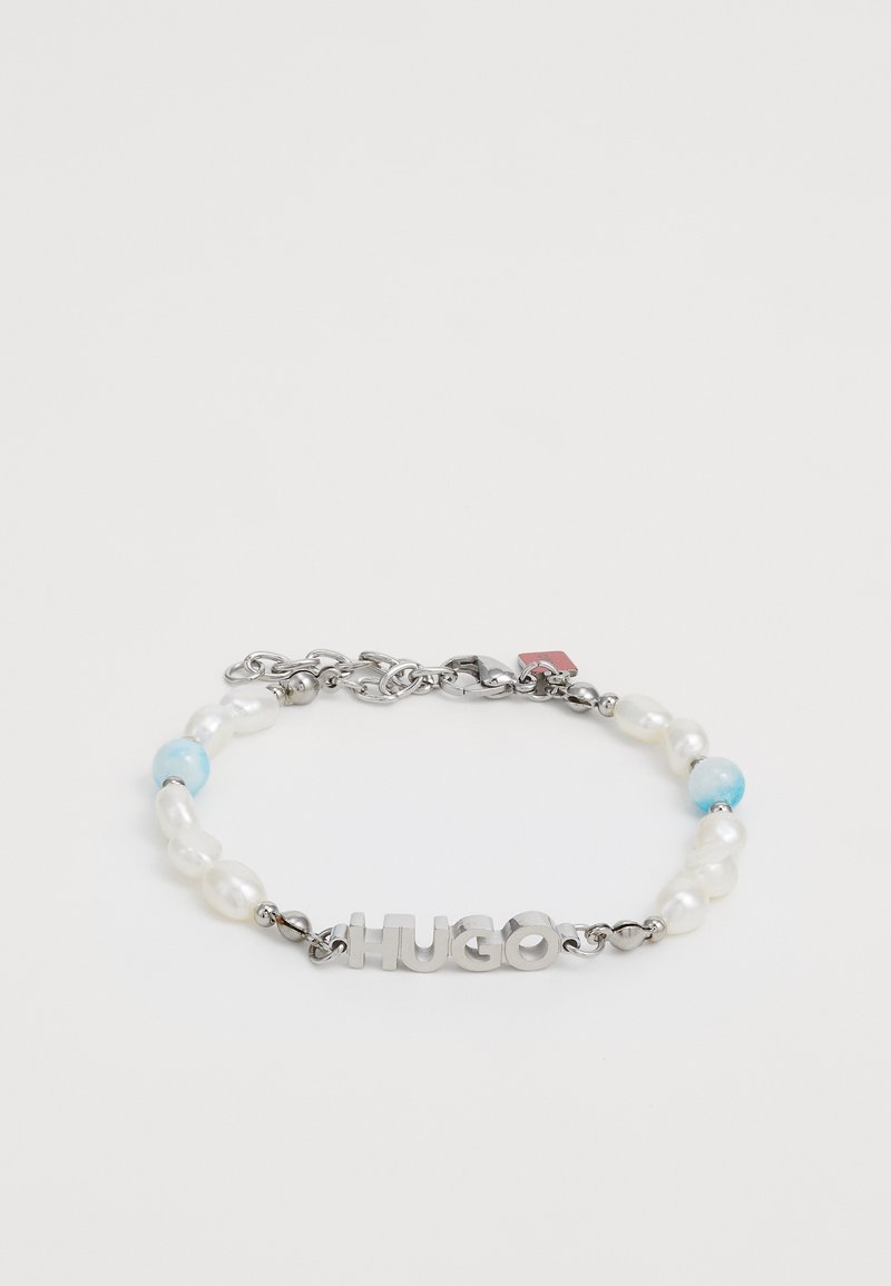 Brățară cu litere metalice "HUGO", perle albe și o bilă albastră, fixată cu un lanț argintiu și un închizător tip homar.