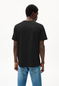 Zwarte katoenen t-shirt met korte mouwen en een relaxte pasvorm. De achterkant toont een eenvoudig ontwerp zonder graphics of opvallende accenten.