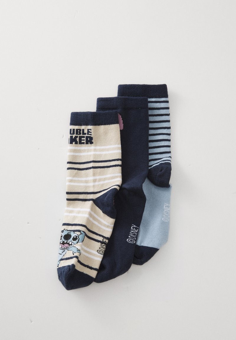 Drei Paar Socken: ein beiges Paar mit navyblauen Streifen und einem Grafikmuster, sowie zwei dunkelblauen Paare (ein einfarbiges und eines mit dünnen hellblauen Streifen).