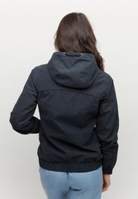 Granatowa, lekka kurtka z kapturem i elastycznym dołem, o gładkiej fakturze i przeszyciach, pokazana z tyłu.