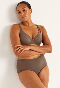 Brun trådlös behå och högmidjade trosor i slät, matt tyg. Enkel, sömlös design med justerbara band, ingen synlig hårdvara.