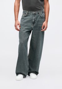 Jeans de pierna ancha en denim gris desgastado con un acabado texturizado, con un diseño clásico de cinco bolsillos y costuras en la cinturilla.