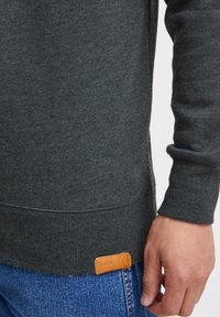 Donkergrijze sweatshirt van zachte stof, met geribbelde mouwen en zoom. Opvallend tan leren label met een reliëf merklogo aan de onderrand.