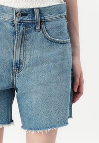 Lichte blauwe denim shorts met rafelige zomen, vijf-pocketdesign en een knoopsluiting. Beschikt over een zachte textuur en een klassieke snit.