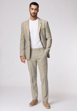 Beige linen suit with a single-breasted blazer and matching trousers. White crew-neck t-shirt underneath. Minimalist design with pockets.