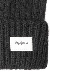 Tamsiai pilkas megztas kepurė su raukšlėta tekstūra ir baltu audiniu etikete, ant kurios užrašyta "Pepe Jeans London."