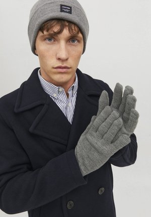 Gray knit gloves with ribbed texture, worn by a person in a navy coat and striped shirt. The beanie also has a gray ribbed design.