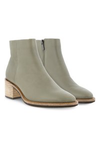 Par de botas de cuero gris claro hasta el tobillo con cremallera lateral y tacones de bloque de madera apilada.