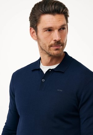 Navyblauwe gebreide polo met een geribde kraag en een placket met drie knopen. Subtiel logo geborduurd op de linkerkant van de borst. Glad textuur.