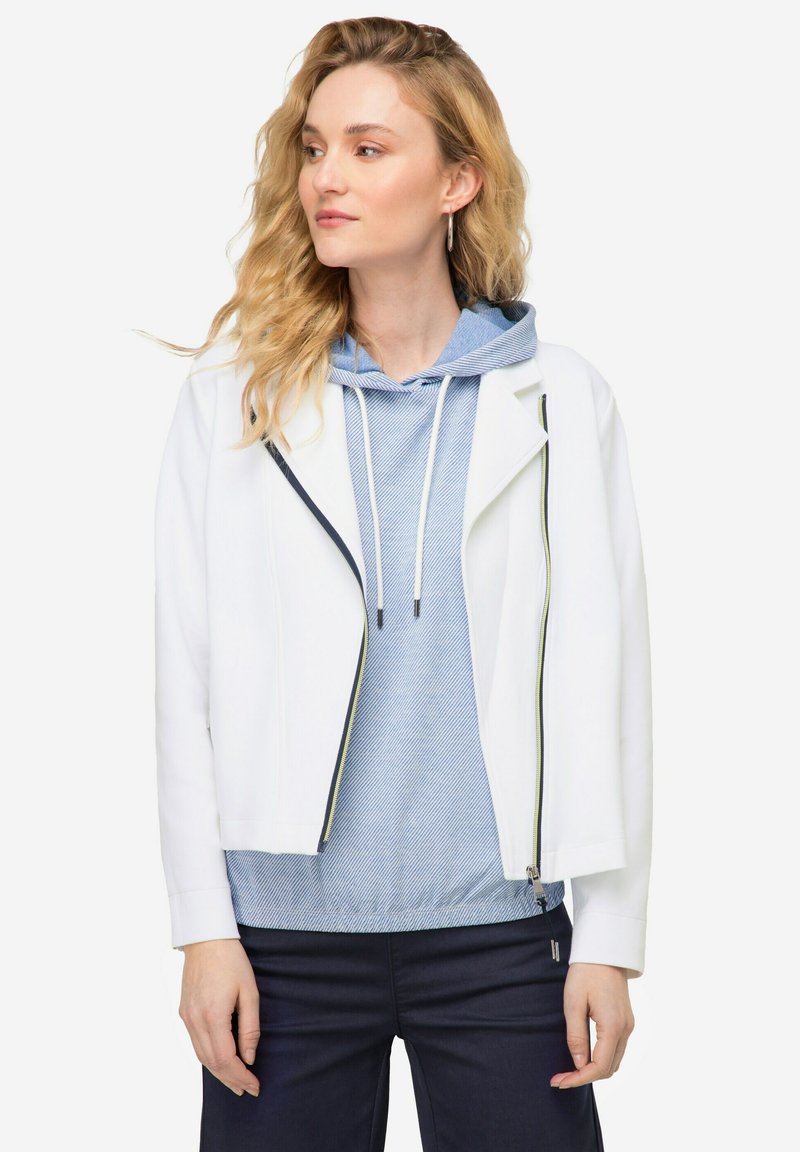 Chaqueta de cuero sintético blanca con un diseño corto y un zipper azul marino. Combinada con un sudadera a rayas azul con capucha y cordón.