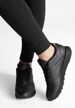 Musthave musta nahast tennisekingad tekstuurse pinnaga, lipsude sulgemise ja paksu kummitald. Kujundust täiendab logo keele ja taga.