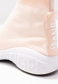 Roze stoffen sneaker met een hoge kraag, gestructureerd breimateriaal en een witte rubberen zool met verhoogde branding.