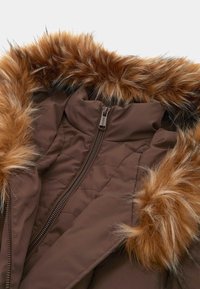 Rudas pūkinis švarkas su dirbtinio kailio kapuce. Tekstūruotas apvadukas aplink kapucę ir užtrauktuką. Dygsniuotas raštas per visą audinį.