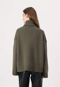 Overdimensjonert olivengrønn genser med høy ribbestrikket krage, strukturert strikk og ribbestrikkede mansjetter, designet med en avslappet passform for komfort.