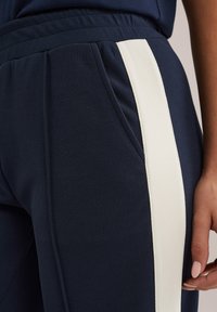 Marina joggers med en strukturerad yta, med en framträdande vit sidremsa och framfickor. Elastisk midja för komfort.