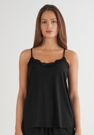 Zwarte geribde cami-top met verstelbare bandjes, voorzien van een gegolfde kanten rand langs de halslijn. Zacht materiaal, losse pasvorm voor comfort.