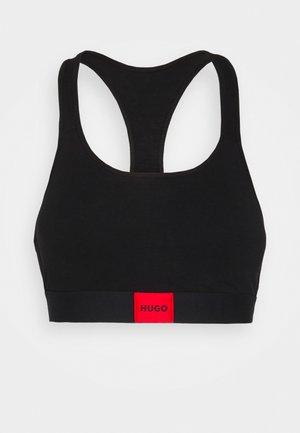 Čierny športový top vyrobený z mäkkého, elastického materiálu. Disponuje strihom s prekríženými ramienkami a červeným logom na spodnej strane pre kontrast.