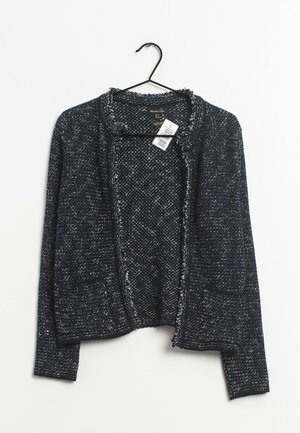 Cardigan tricoté texturé bleu foncé à manches longues et devant ouvert, suspendu à un cintre noir sur fond blanc.
