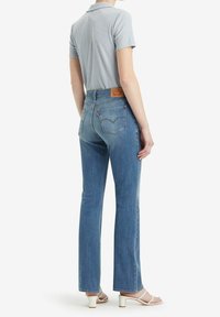 Jeans en denim bleu avec une coupe droite, taille haute et poches arrière. Assortis à un haut à col bleu clair à manches courtes.