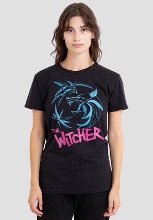 Schwarzes Baumwoll-T-Shirt mit einem blauen Grafikdesign von Wölfen und dem Text "THE WITCHER" in Pink. Kurzärmlig, Standardpassform.