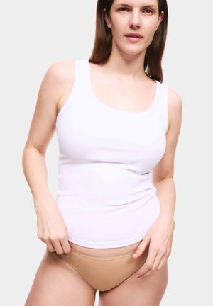 Witte geribbelde tanktop met brede banden, gecombineerd met beige panties. De hand van het model past de tailleband aan, op een neutrale achtergrond.