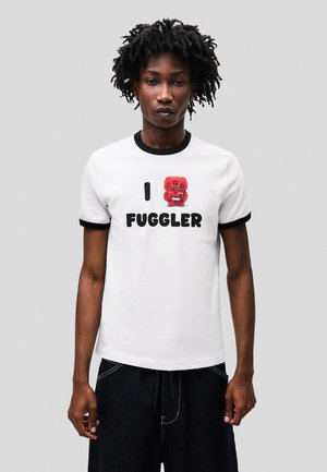 White cotton t-shirt with black ribbed collar and sleeves. Features a red graphic of a creature and bold black text reading “I FUGGLER.”
