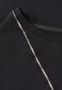 Sort T-shirt med rund hals, glat tekstur og en metalgrå stribe langs skuldersømmen, hvilket tilføjer visuel kontrast.