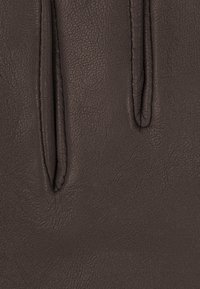 Texture de cuir marron avec un grain de surface visible. Présente deux ouvertures étroites et une sensation douce et souple. Pas de quincaillerie ni de motifs présents.
