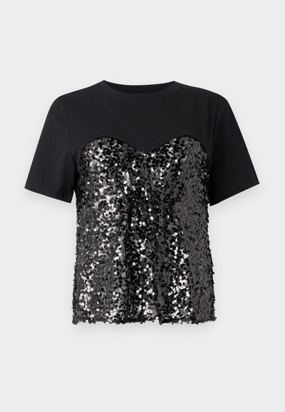 T-shirt nero con un corpetto decorato con paillettes a forma di cuore. La parte superiore è liscia, in contrasto con la parte inferiore testurizzata.