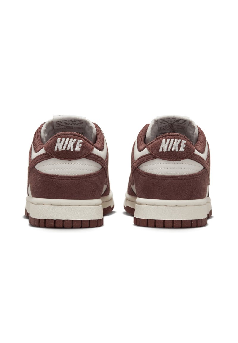 Zapatillas Nike con parte superior de gamuza burdeos y acentos de cuero blanco. Incluye características como collar acolchado, logo cosido y suela de goma.