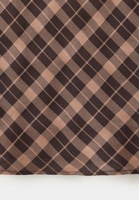 Gros plan sur un tissu à carreaux marron et beige avec un motif à carreaux diagonal et des lignes tissées texturées.